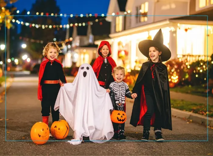 Kids in their Halloween costumes walking in the street during early evening.