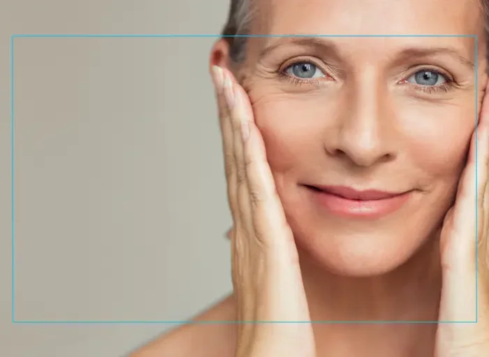 Close up of a woman smiling with her hands on either side of her face