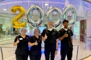 Dr Filutowski and staff giving a thumbs up in front of balloons that spell out 2000