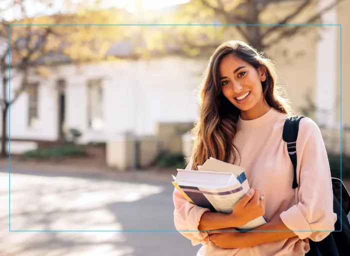 College student walking across campus with books, representing the importance of vision care and eye health preparation before starting college.